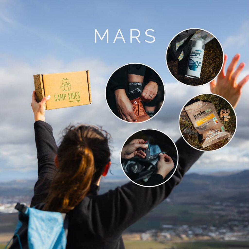 Visuel unboxing de la box Camp Vibes de mars 2024, avec une femme tenant la box en l'air devant un paysage montagneux