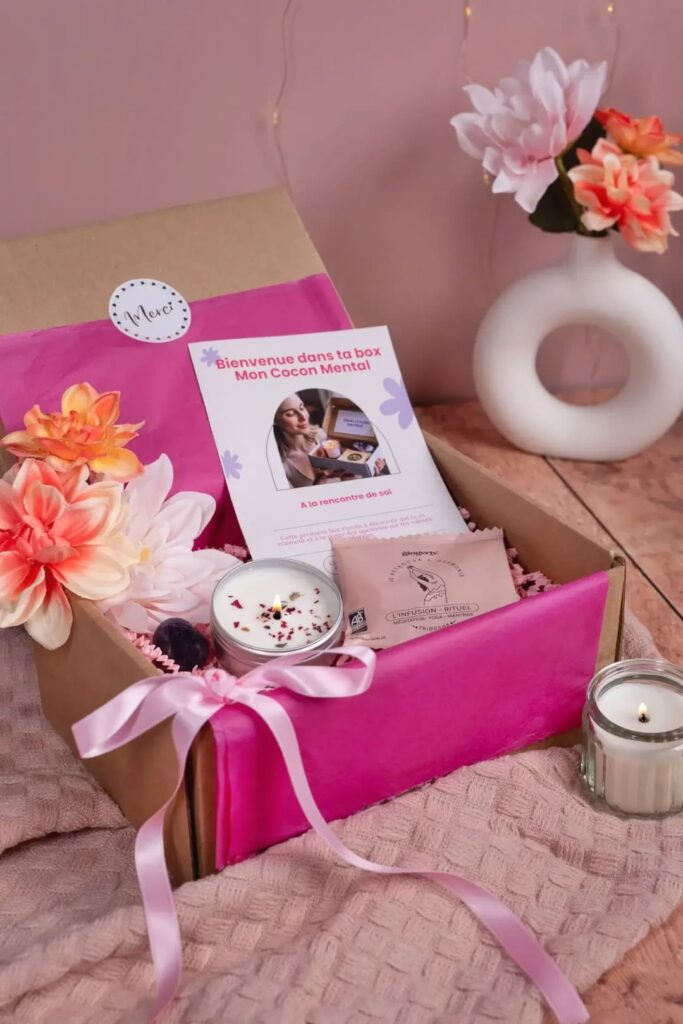 Coffret bien-être ouvert avec bougie parfumée, infusion, livret d’accueil et décoration florale
